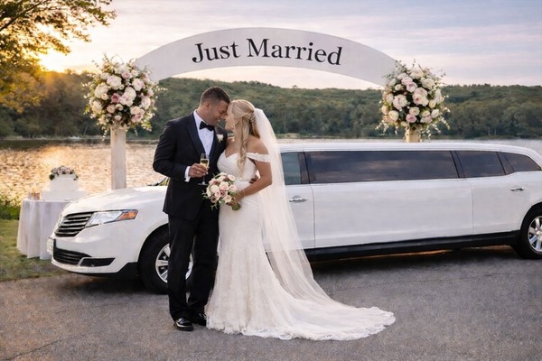 Bride and groom entering limousine at Boston wedding venue